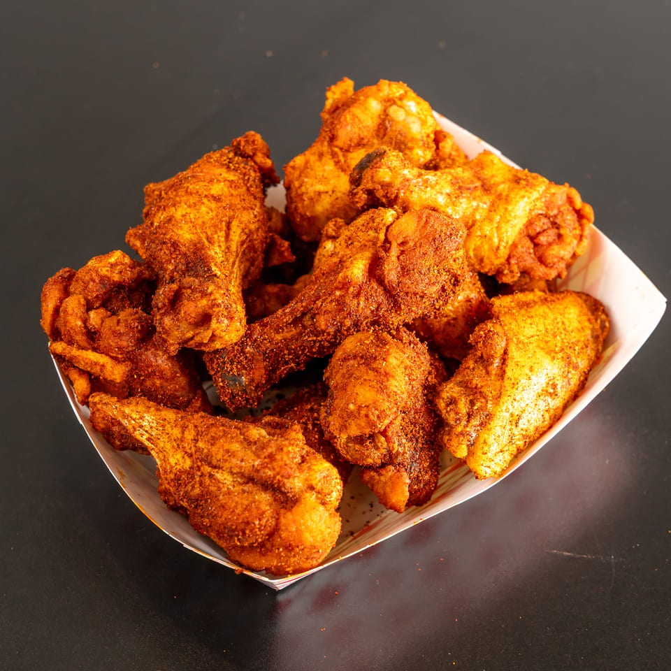 Basket filled with assorted golden-brown seasoned fried chicken pieces on a dark tabletop.